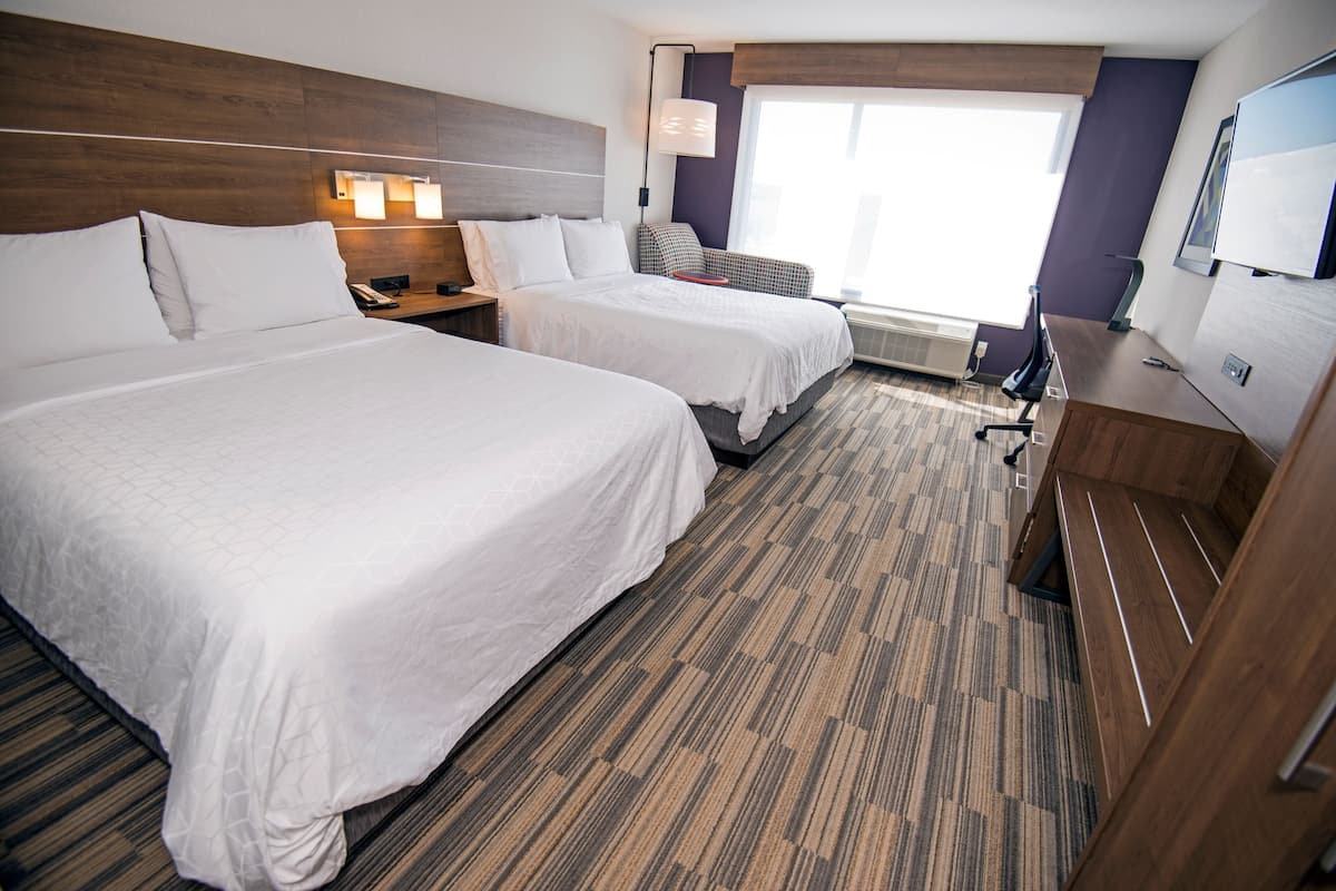 Une chambre d’hôtel avec deux lits, un bureau, une chaise, une télévision et une fenêtre donnant sur un beau paysage.