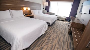 Habitación de hotel con dos camas, un escritorio, una silla, un televisor y una ventana con persianas.