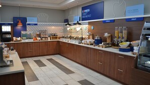 A modern breakfast area with a counter, various food stations, and a coffee machine. - Holiday Inn Express Red Deer North by IHG (Red Deer)