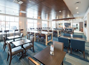 A spacious indoor dining area with multiple tables and chairs, large windows, and a modern ceiling design. - Holiday Inn Express Red Deer North by IHG (Red Deer)