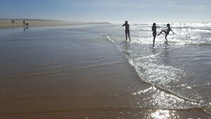 Een strand met mensen die wandelen en in het water spelen.