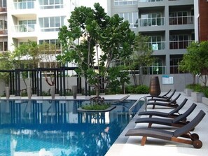 A swimming pool with lounge chairs and a tree in the center. - The Seacraze Hua Hin by Montri (Hua Hin)