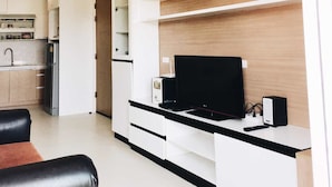 A modern living room with a flat-screen TV, a coffee machine, and a built-in bookshelf. - The Seacraze Hua Hin by Montri (Hua Hin)