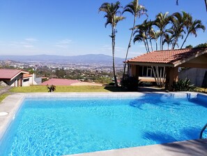A swimming pool with a clear view of a cityscape and mountains in the background.