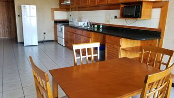 A kitchen with wooden cabinets, a stove, a microwave, and a dining table with chairs.