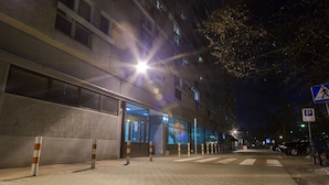 Vista nocturna de un edificio con una señal de paso de peatones y una señal de estacionamiento.