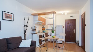Un espacio habitable pequeño con sofá, mesa de comedor y kitchenette.