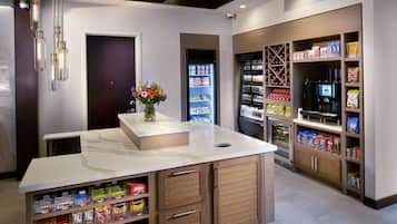 A modern kitchen with a marble countertop, wooden cabinets, and a built-in coffee machine.