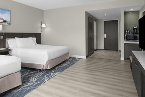 A hotel room with a bed, bedside tables, a flat-screen TV, a microwave, and a small kitchenette. - Hilton Garden Inn Roslyn (Port Washington)