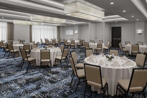 A conference room with round tables, chairs, and a patterned carpet. - Hilton Garden Inn Roslyn (Port Washington)
