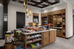 A well-organized snack bar with a variety of food items and beverages, a freezer section, and a coffee machine. - Hilton Garden Inn Roslyn (Port Washington)