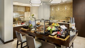 A breakfast bar with a variety of food items, a coffee machine, and a waffle maker. - Hilton Garden Inn Roslyn (Port Washington)