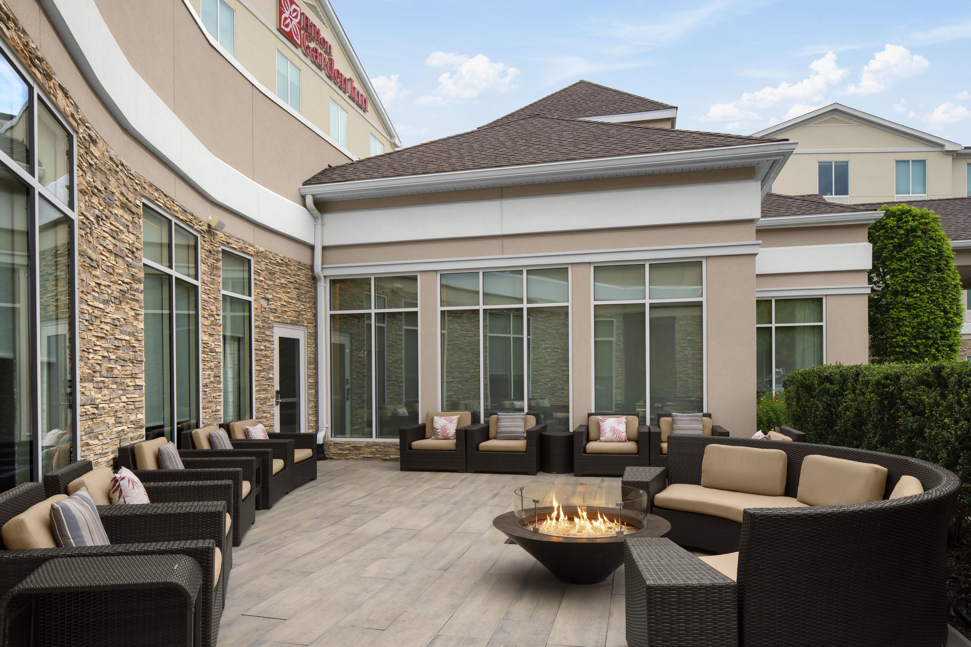 Un patio de hotel con mobiliario de mimbre, una chimenea y ventanas grandes.