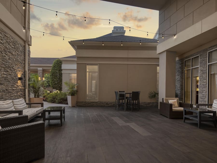 An outdoor patio area with stone walls, a seating arrangement, and string lights.