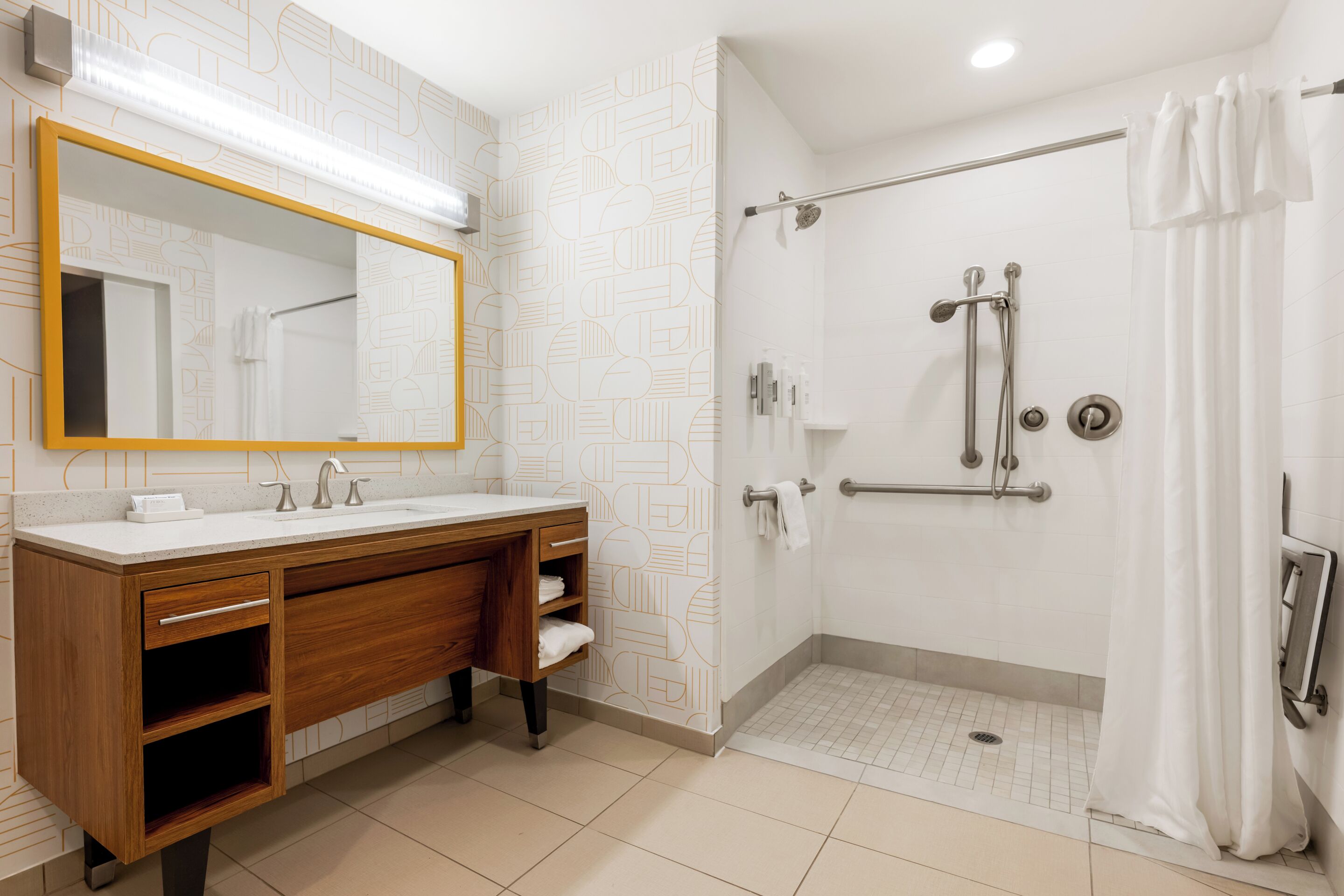 A modern bathroom with a vanity, a shower with a glass door, and a large mirror.