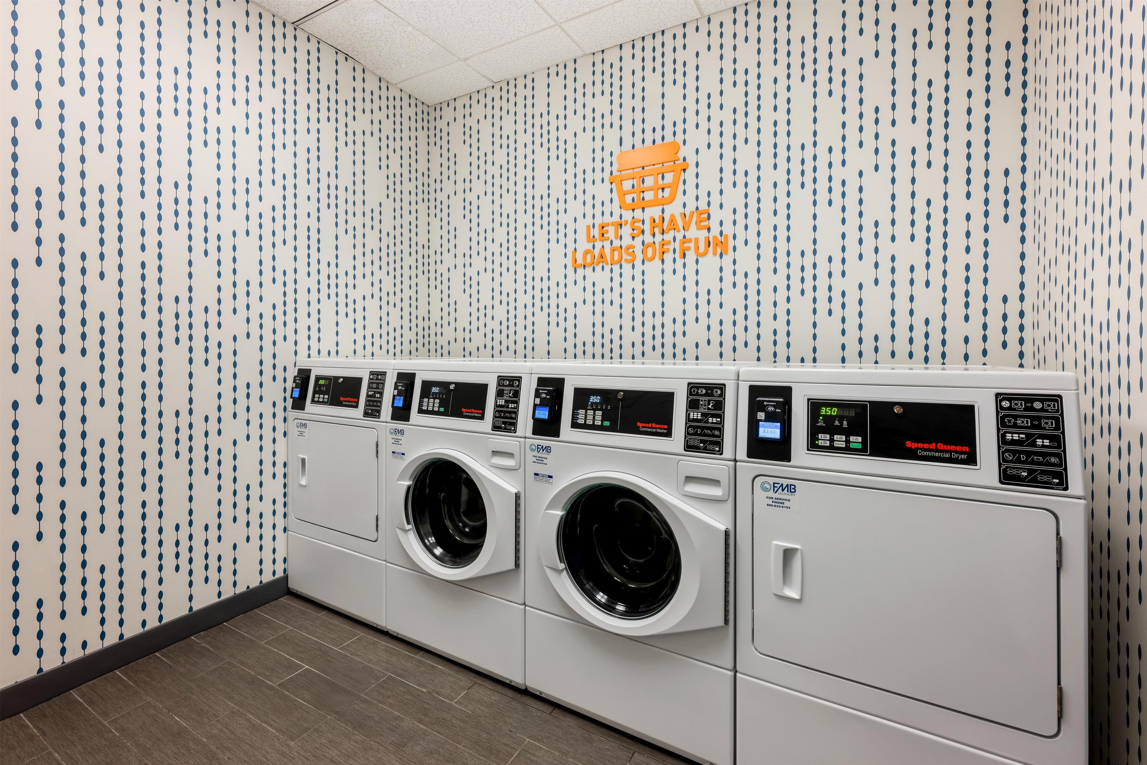 A laundry facility with multiple washing machines and a wall with a pattern of blue dots.