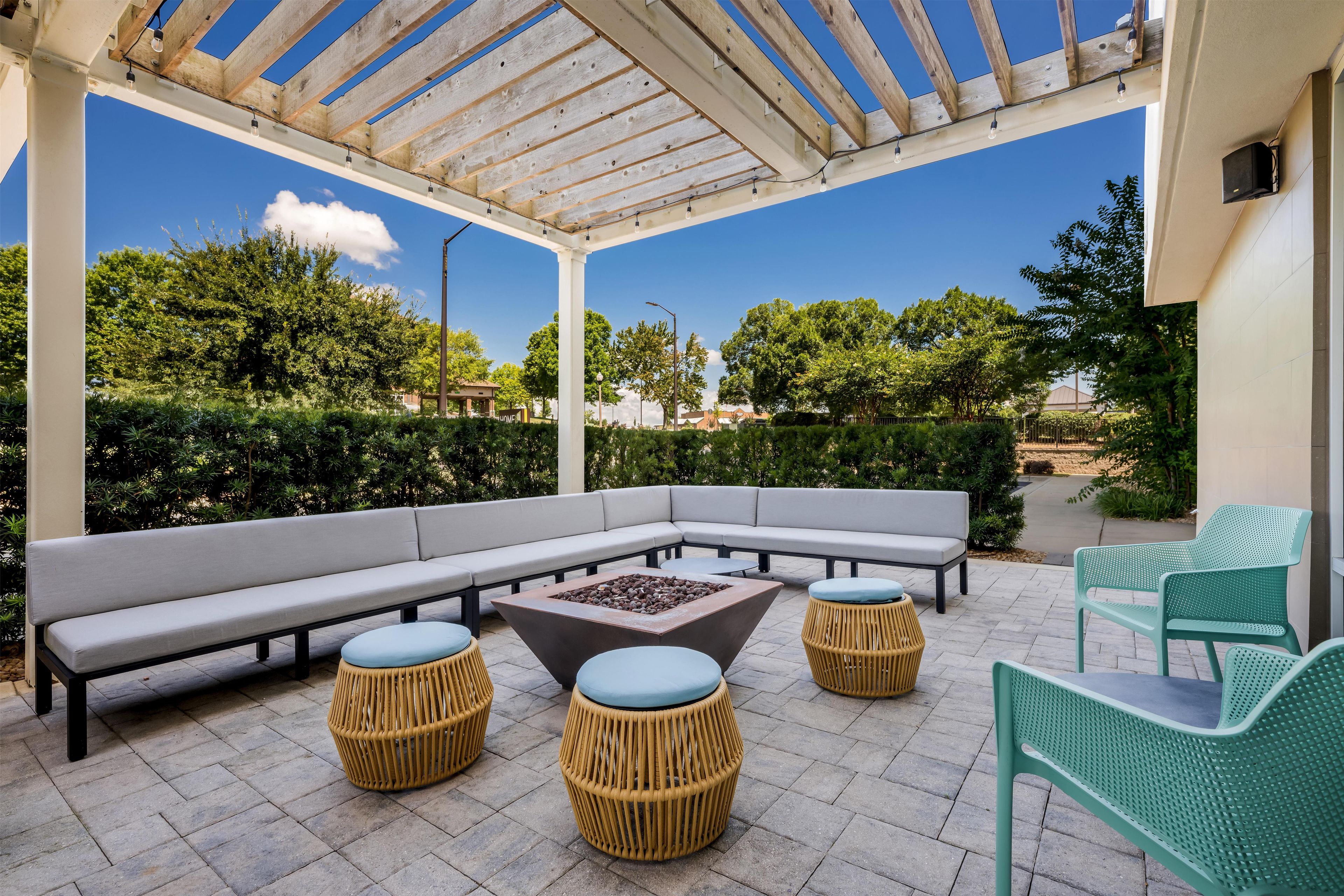 Un patio al aire libre con un sofá sectional, otomanos redondos y una chimenea.