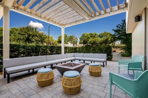 Un patio al aire libre con un sofá sectional, otomanos redondos y una chimenea.