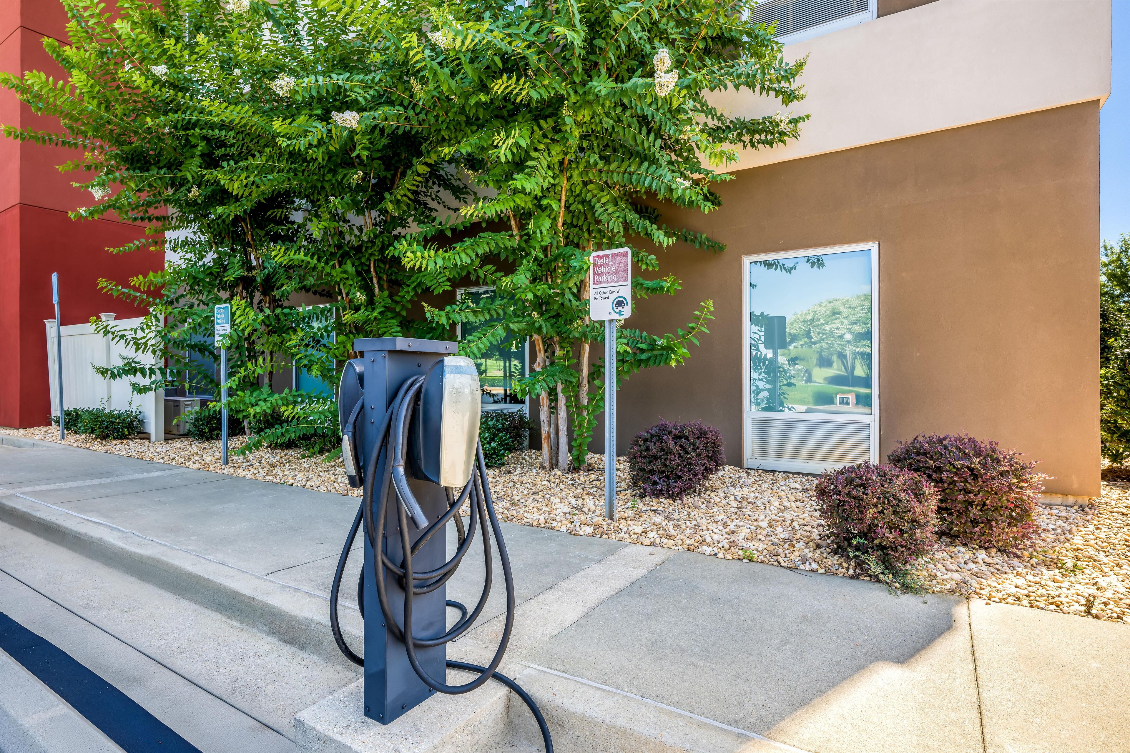 Una estación de carga de Tesla con un cartel que indica que es solo para vehículos Tesla, y un cartel aparte para estacionamiento de vehículos eléctricos.