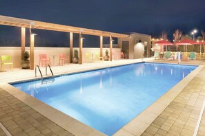 En swimmingpool med ett trädäck och en utomhusplats med sittmöbler.
