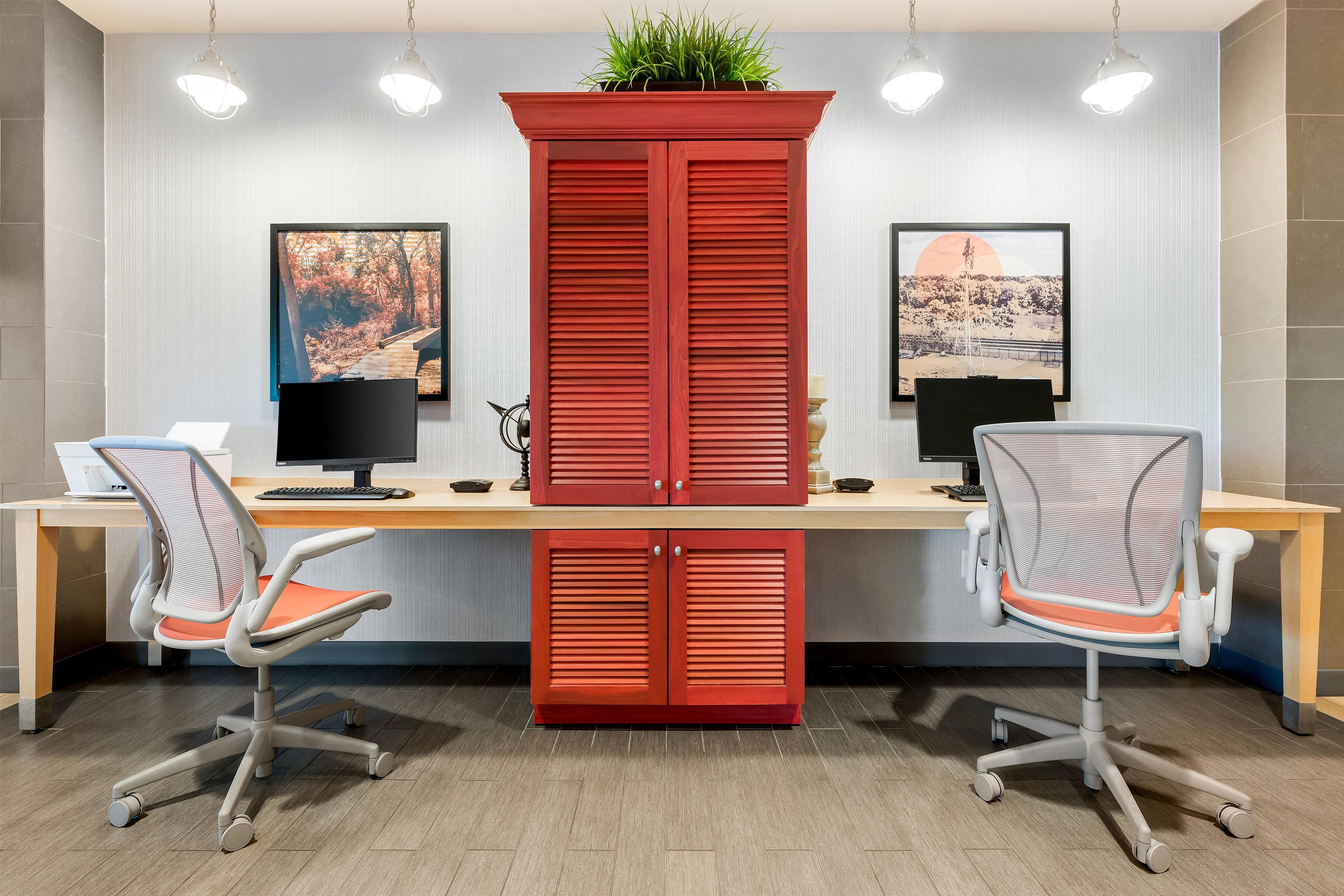 A modern office with two desks, chairs, and two monitors.