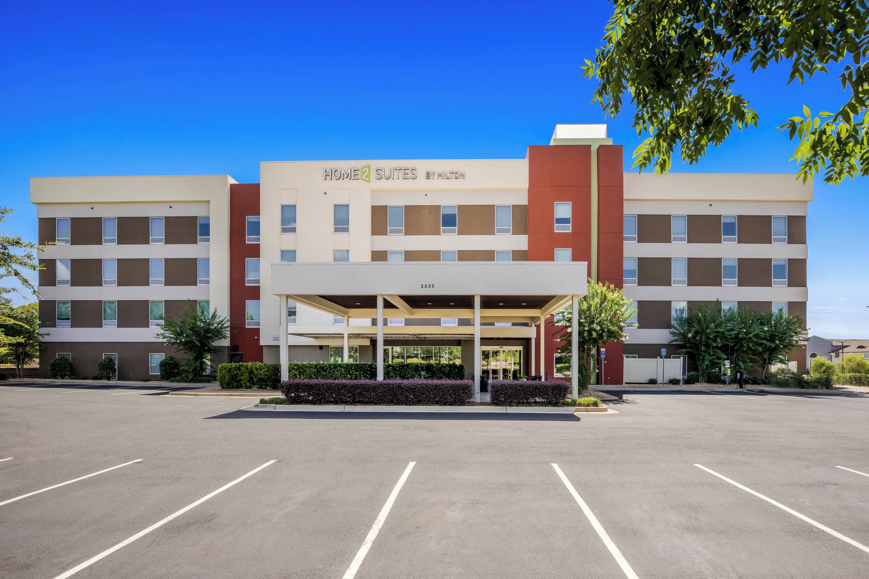 A hotel with a covered entrance, multiple floors, and a parking lot.