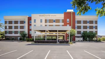 A hotel with a covered entrance, multiple floors, and a parking lot.