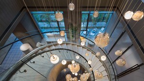 A modern interior with a glass spiral staircase and hanging spherical light fixtures. - Hilton Quanzhou Riverside (Quanzhou)