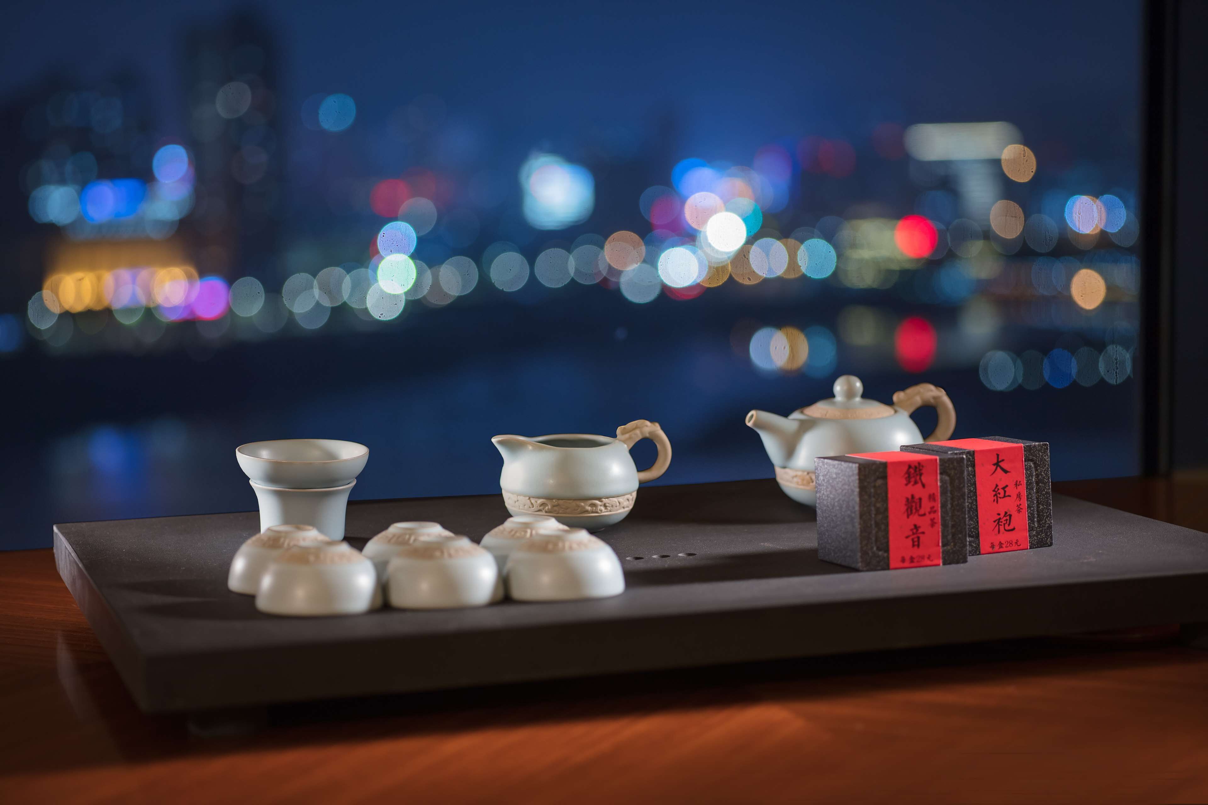 A traditional tea set on a tray with a cityscape view in the background.