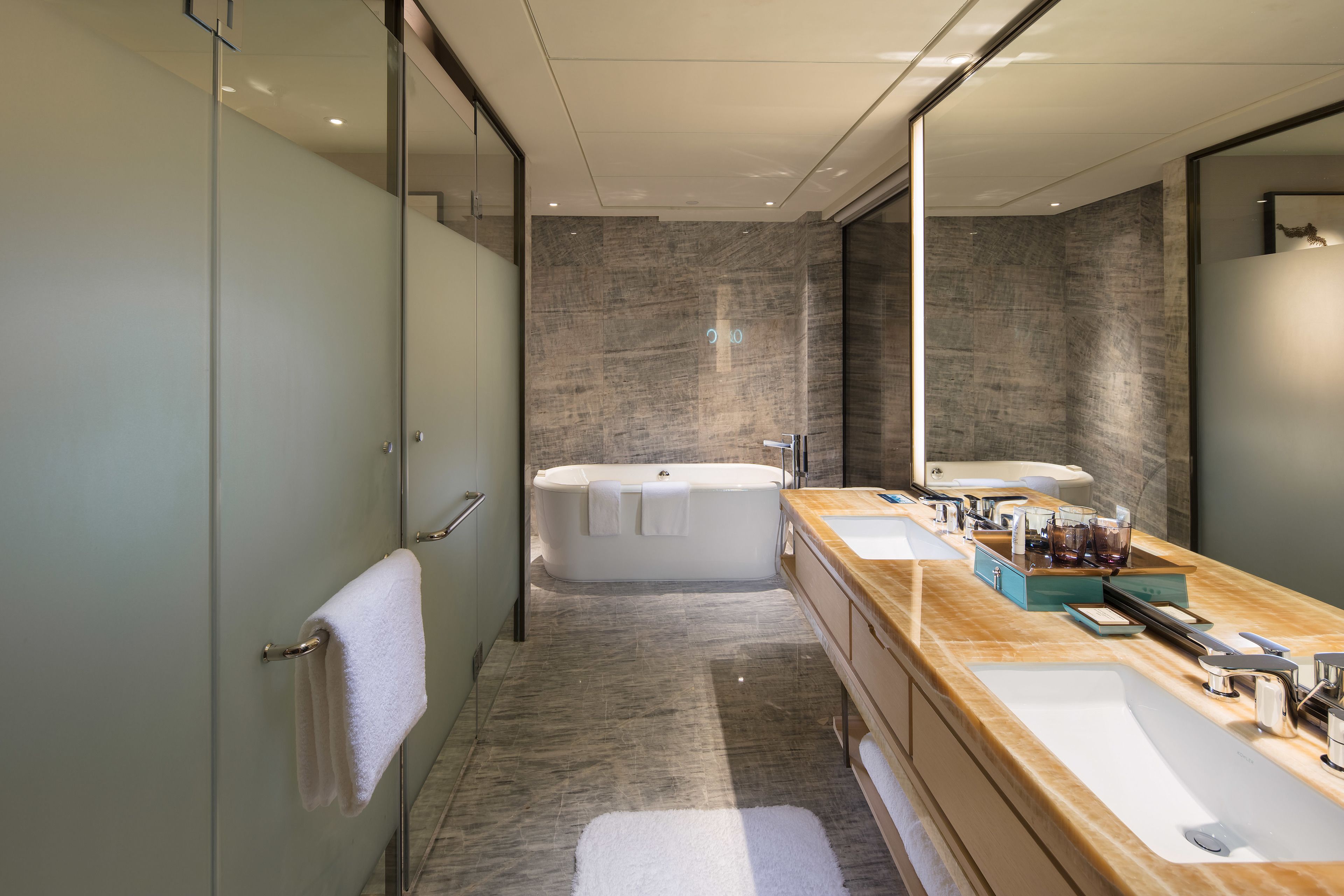 A modern bathroom with a large bathtub, two sinks, and a vanity with toiletries.