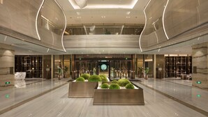 A spacious lobby with a central seating area, a high ceiling with modern lighting, and a view of the lobby area through the glass doors. - Hilton Quanzhou Riverside (Quanzhou)