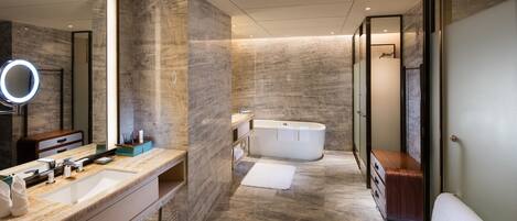 Une salle de bain moderne avec un grand miroir, une baignoire et un meuble-lavabo doté d’un évier et d’un porte-serviettes.