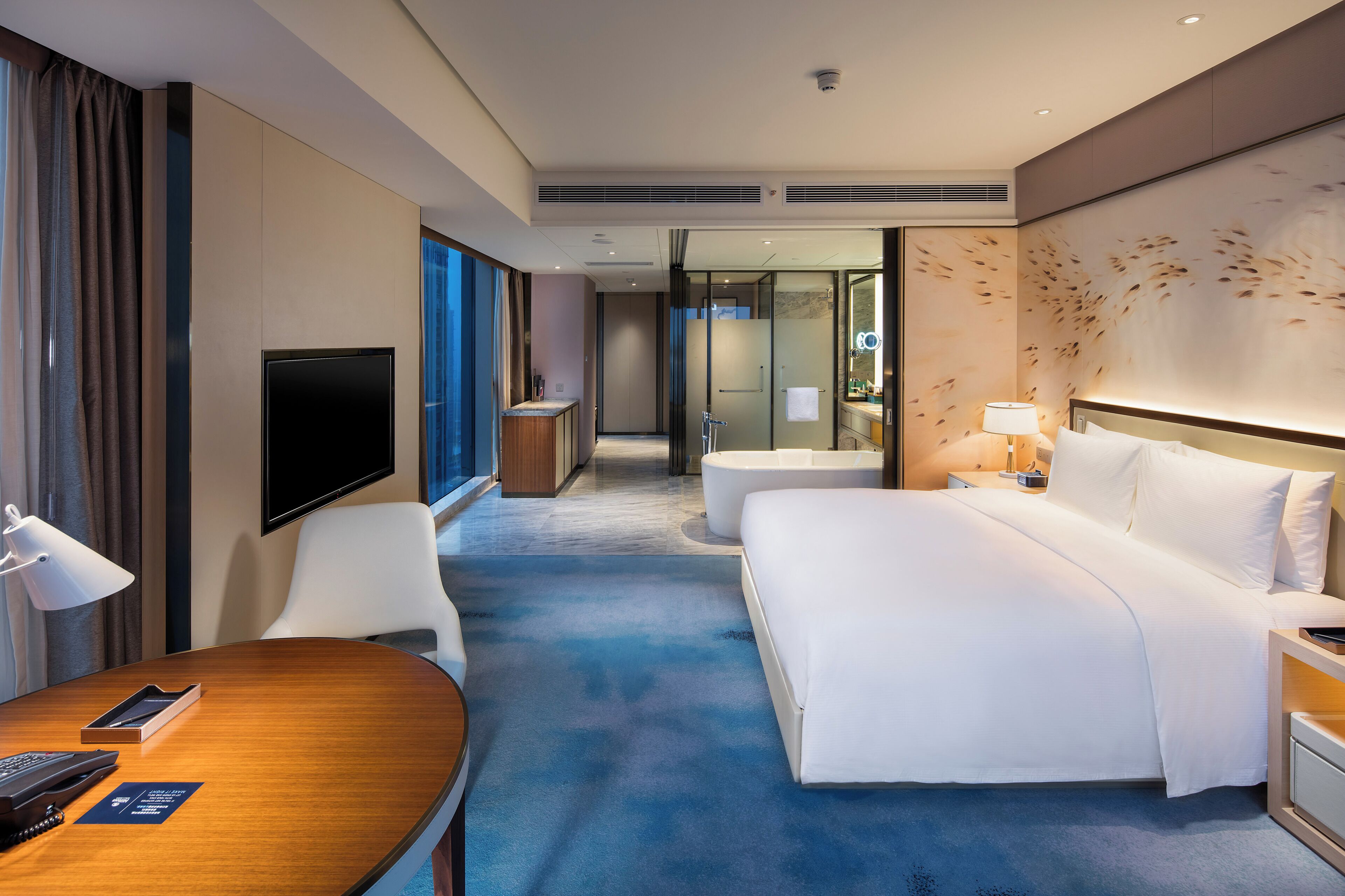 A hotel room with a bed, a desk, a television, and a bathroom.