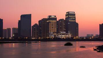 A city skyline with high-rise buildings, including a Hilton hotel, at dusk.