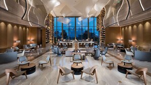 A modern hotel lobby with a central seating area, a bar, and a large window offering a city view. - Hilton Quanzhou Riverside (Quanzhou)