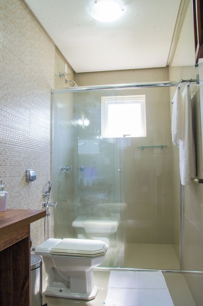 A bathroom with a glass-enclosed shower, a toilet, and a sink.