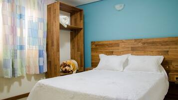 A bedroom with a wooden headboard, a bed with white linens, a nightstand, and a wooden wardrobe.