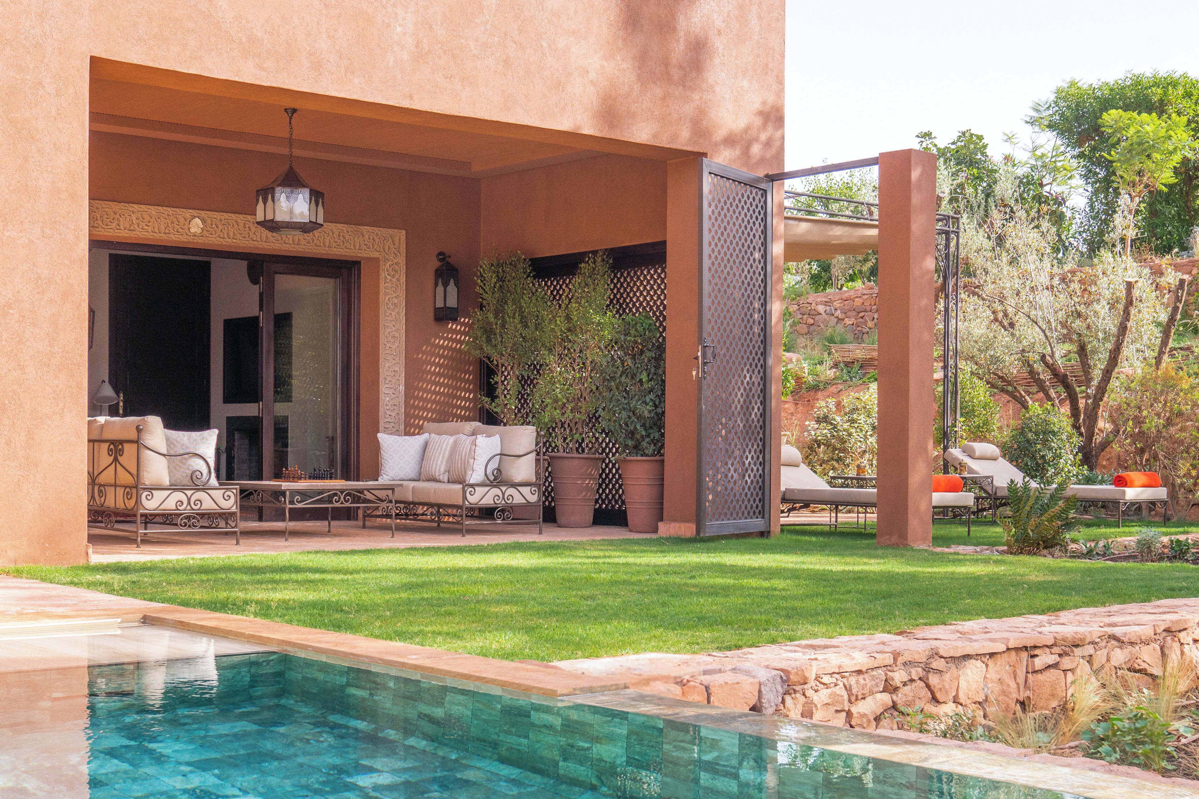 A poolside area with a lounge chair, a sofa, and a pergola.