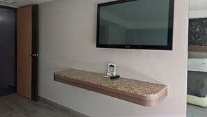 Moderni kylpyhuone, jossa on sisäänrakennettu graniittitaso, seinälle asennettu Samsung-televisio ja puuovi.