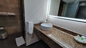 A modern bathroom with a granite countertop, a white sink, and a large mirror.