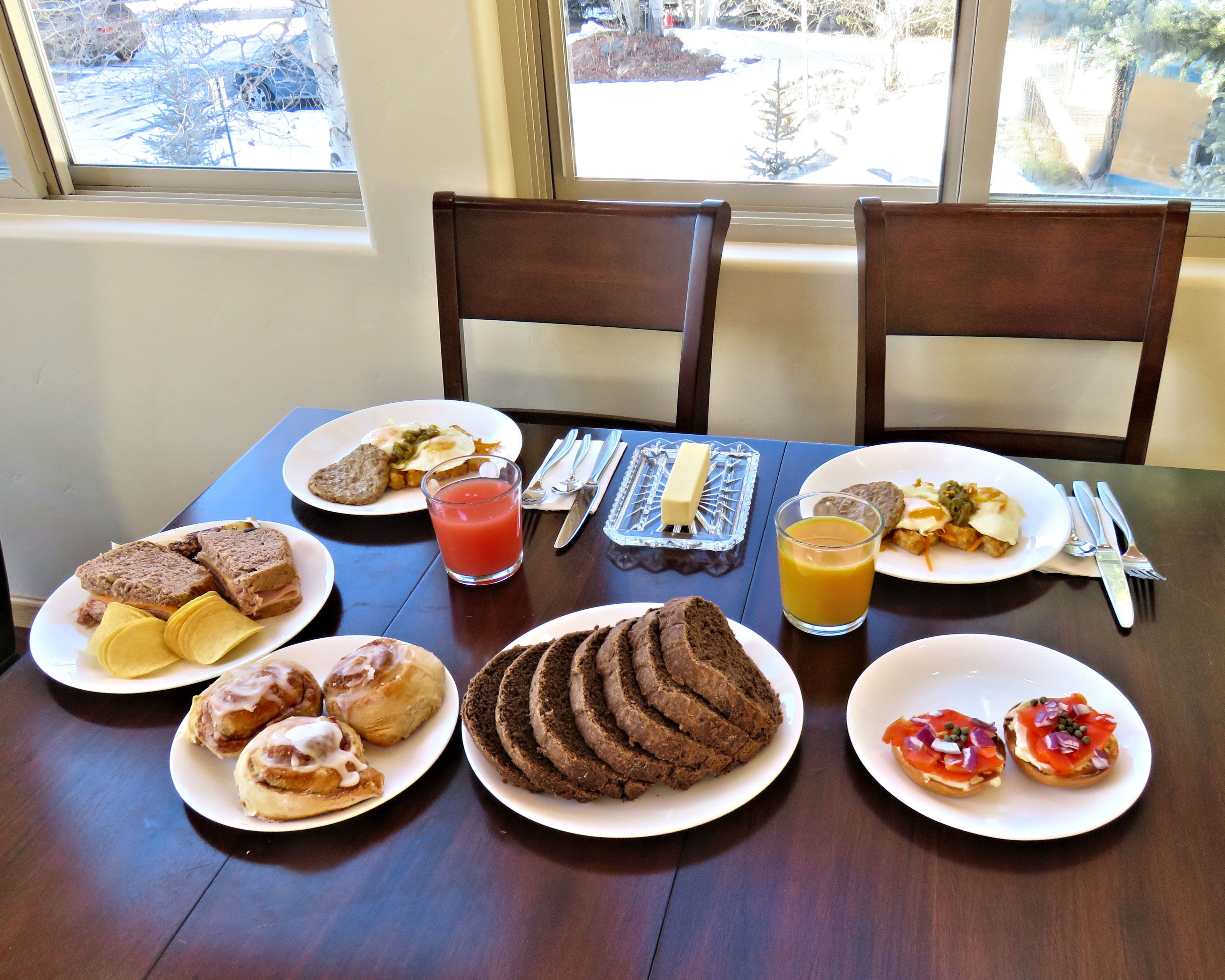 Et morgenbord med tallerkener med mad, et glas juice og bestik.