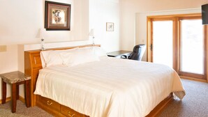 A bedroom with a large bed, wooden headboard, a desk, and a chair. - Mein Haus Bed & Breakfast (Avon)