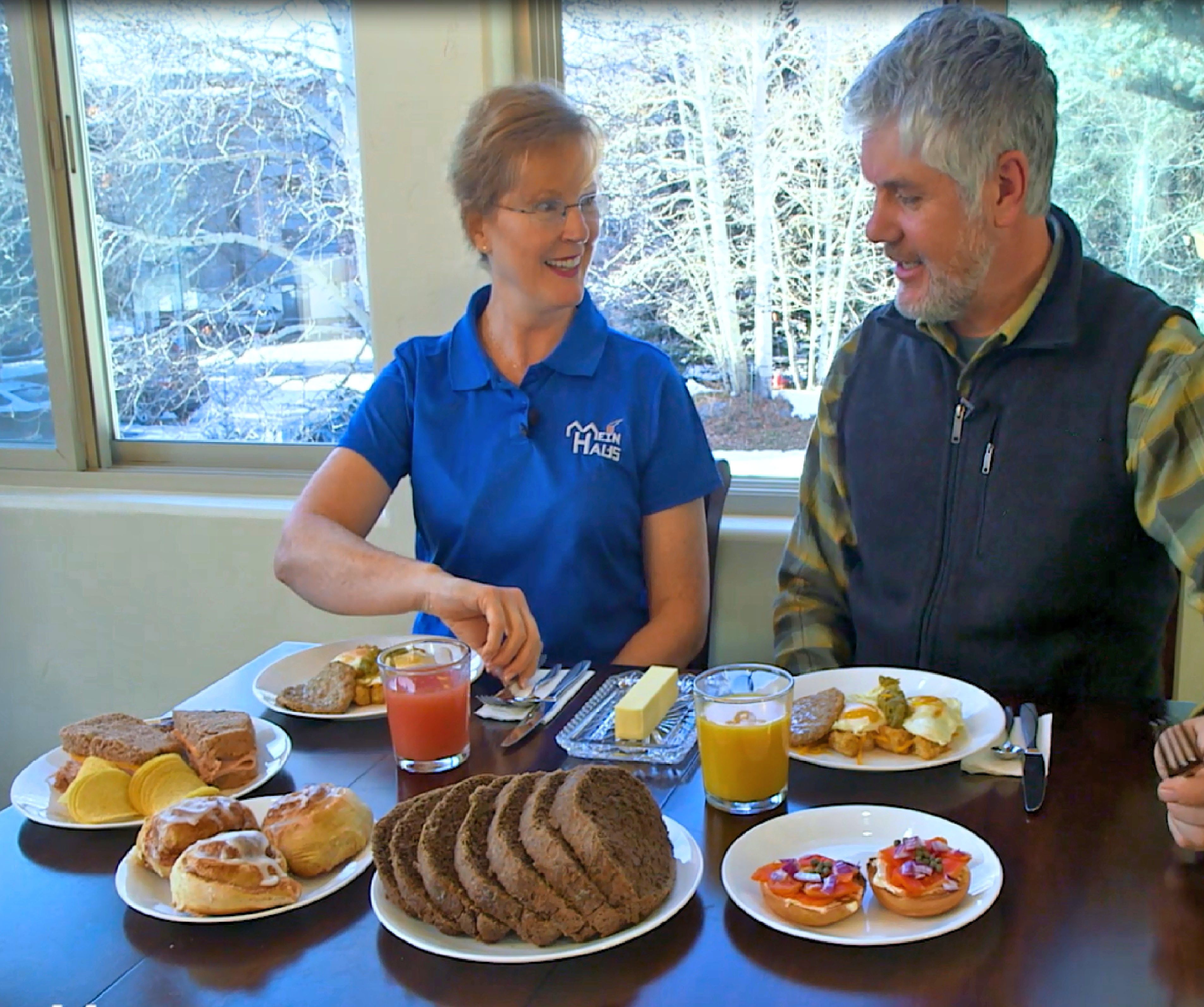 A dining table with various breakfast items including pastries, a glass of orange juice, and a plate of eggs.