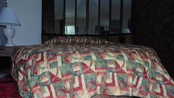 A bedroom with a large bed, a curved headboard, and a mirror above the bed.