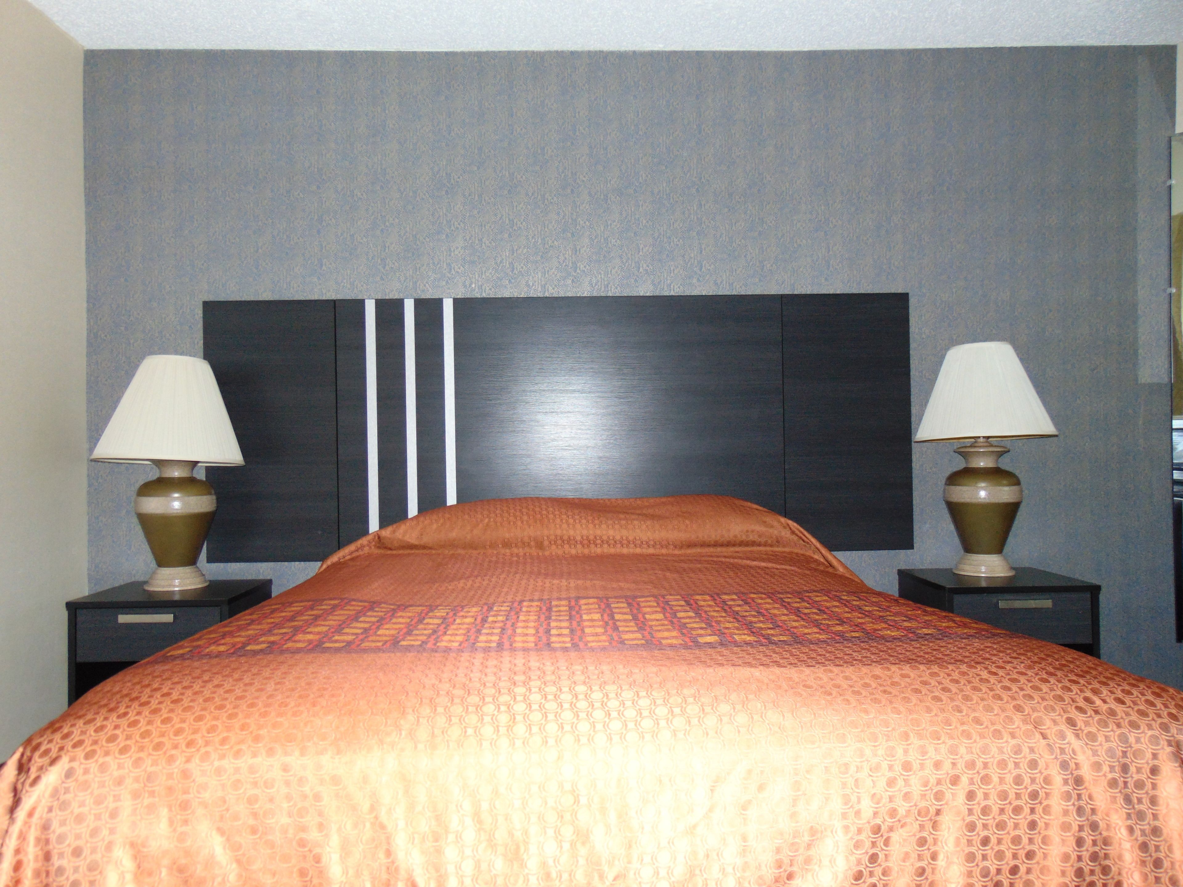 A hotel room with a large bed, two bedside tables, and two lamps.