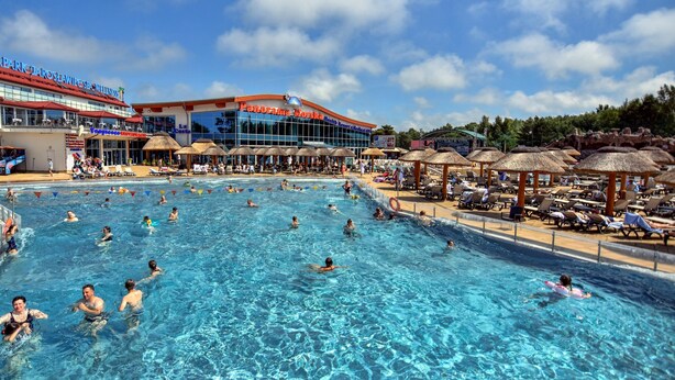 Une grande piscine extérieure avec plusieurs couloirs de nage, entourée de parasols et de chaises longues.