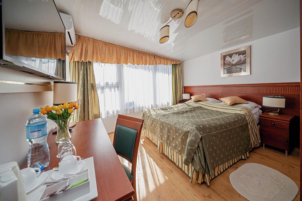 Una habitación de hotel con cama, mesita de noche, lámpara y un cuadro en la pared.