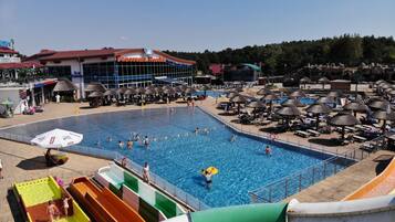 Zona de piscina con toboganes, sombrillas y sillones reclinables.