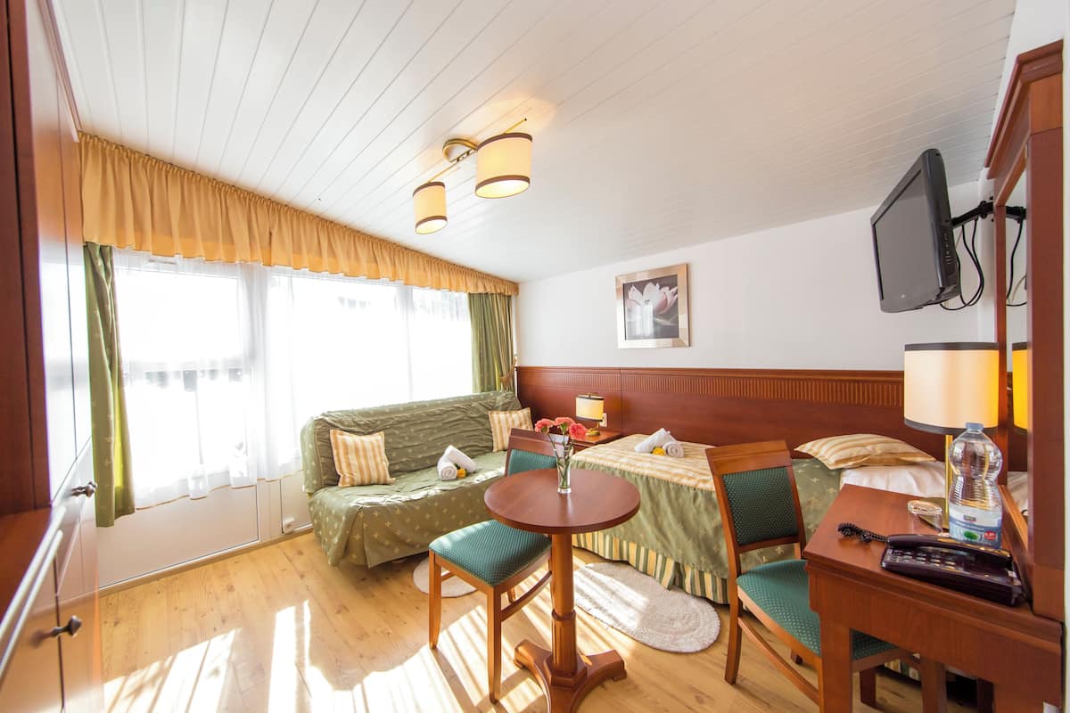 Una habitación con cama, sofá, mesa y televisor.