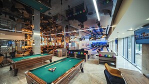 Une salle de billard avec plusieurs tables, une piste de bowling et un espace bar.
